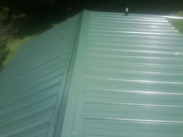 New green metal panels meeting at the ridge of a roof — Flat Roof Repair work by our crew in Steamboat Rock