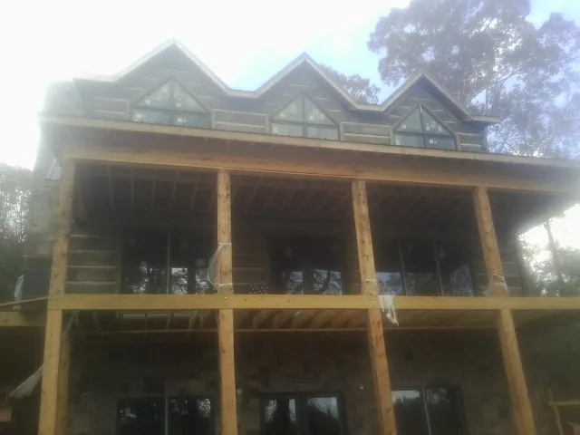 Dormers and porch framing on a large log home under construction — Roof Coating work by our crew in Steamboat Rock