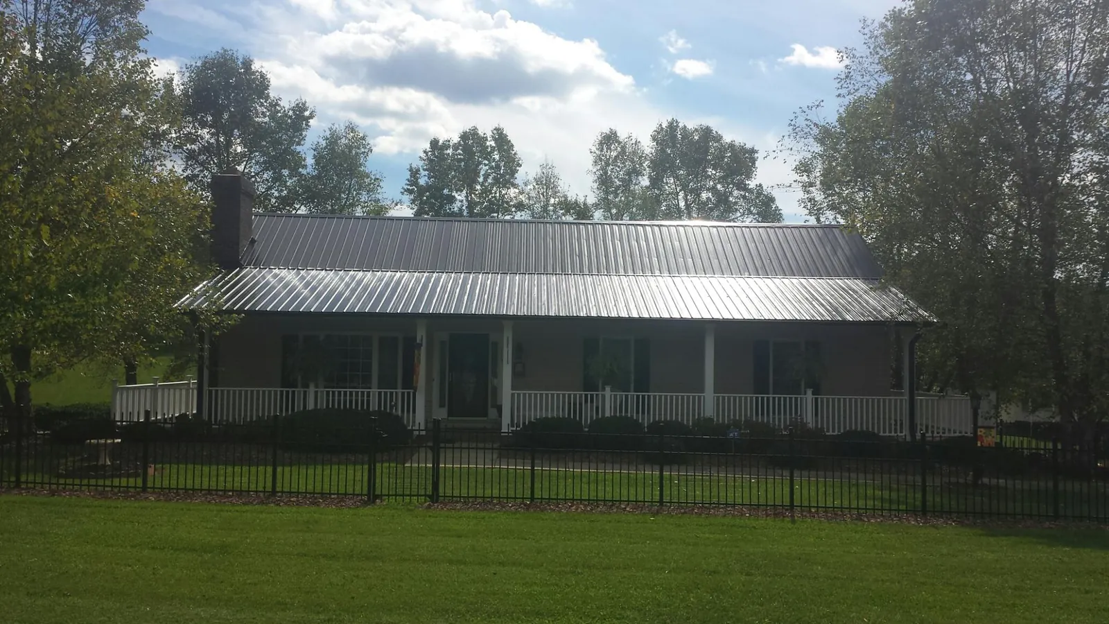 Gray metal roof on a brick ranch with a full width front porch — Gutter Guard Installation work by our crew in Steamboat Rock