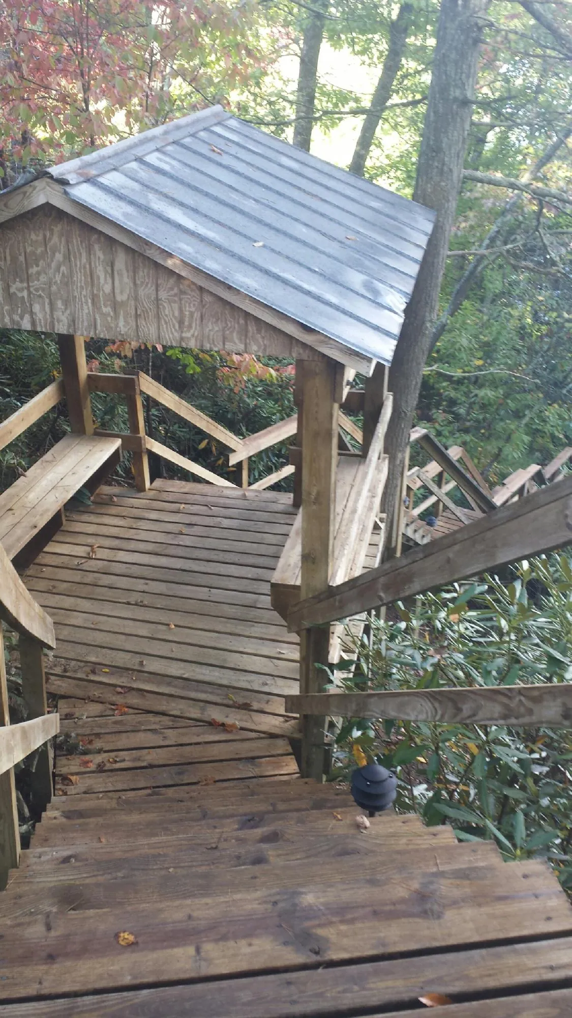 Metal roofed shelter over wooden steps on a wooded walkway — Skylight Repair & Installation work by our crew in Steamboat Rock