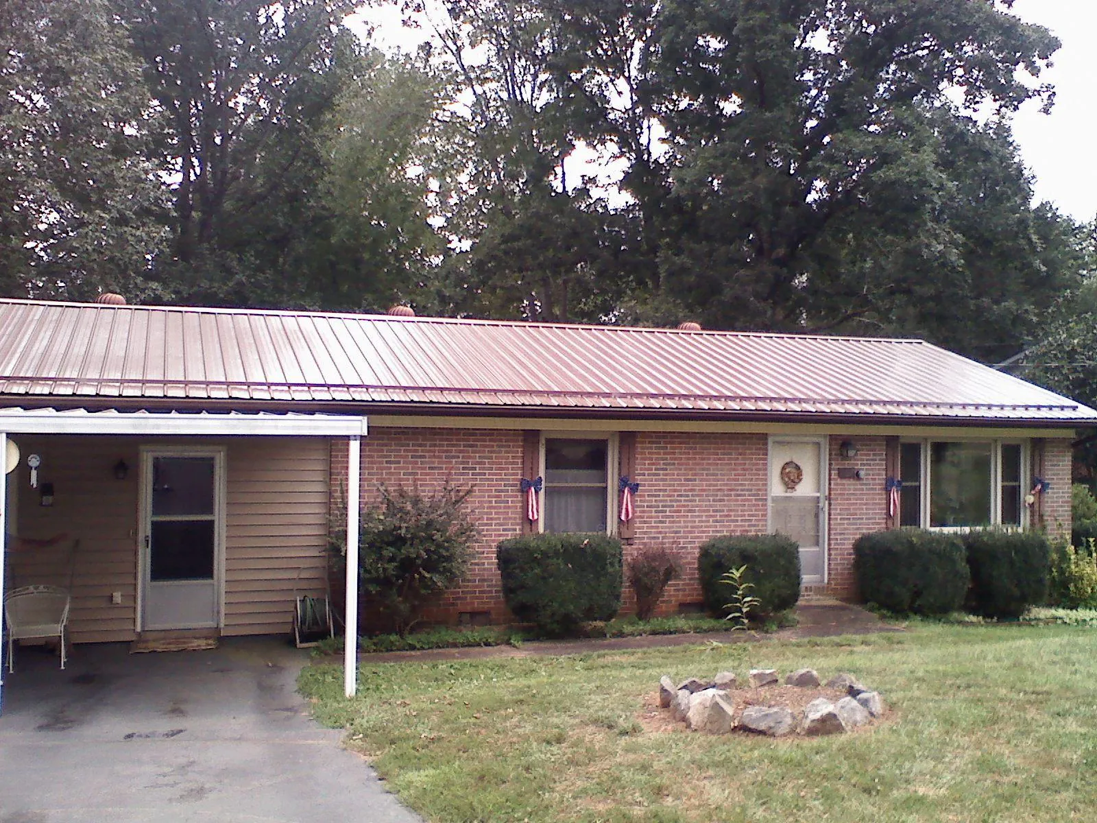 Bronze metal roof and carport on a brick ranch home — Roof Repair work by our crew in Steamboat Rock